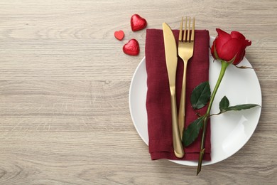 Romantic place setting with red rose on wooden table, top view. Valentine's day celebration