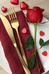 Photo of Romantic place setting with red rose on wooden table, top view. Valentine's day celebration