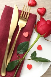 Romantic place setting with red rose on wooden table, top view. Valentine's day celebration