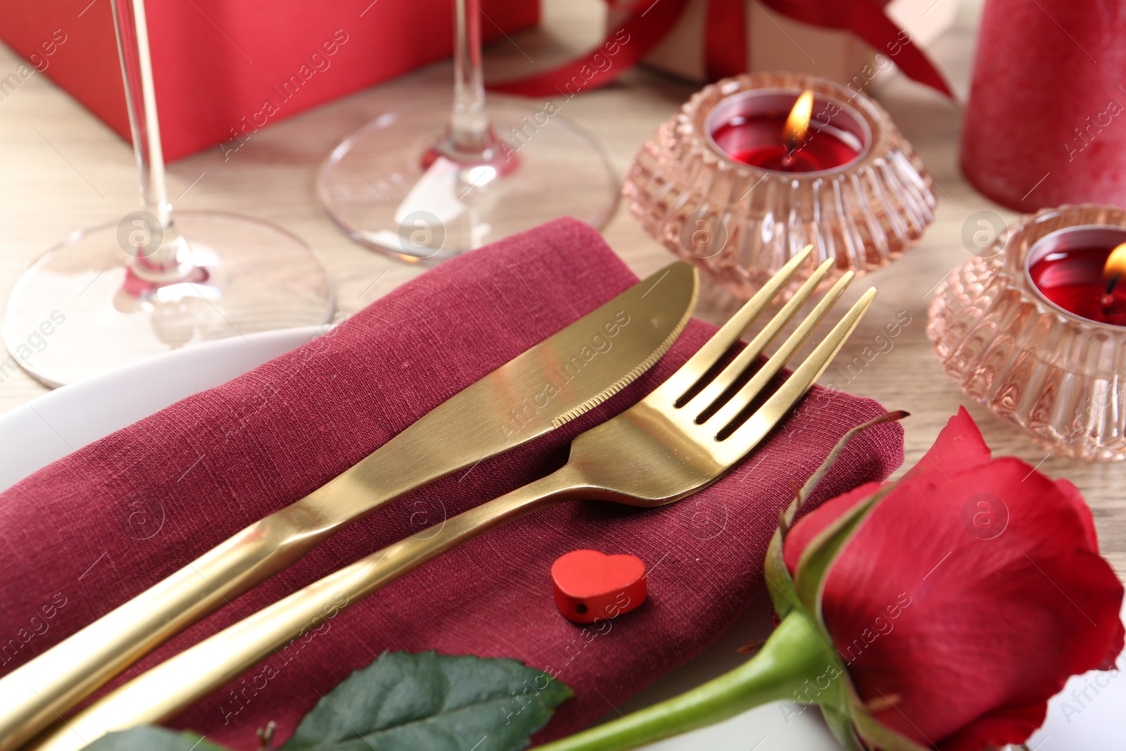 Photo of Romantic place setting with red rose on white table, closeup. Valentine's day celebration