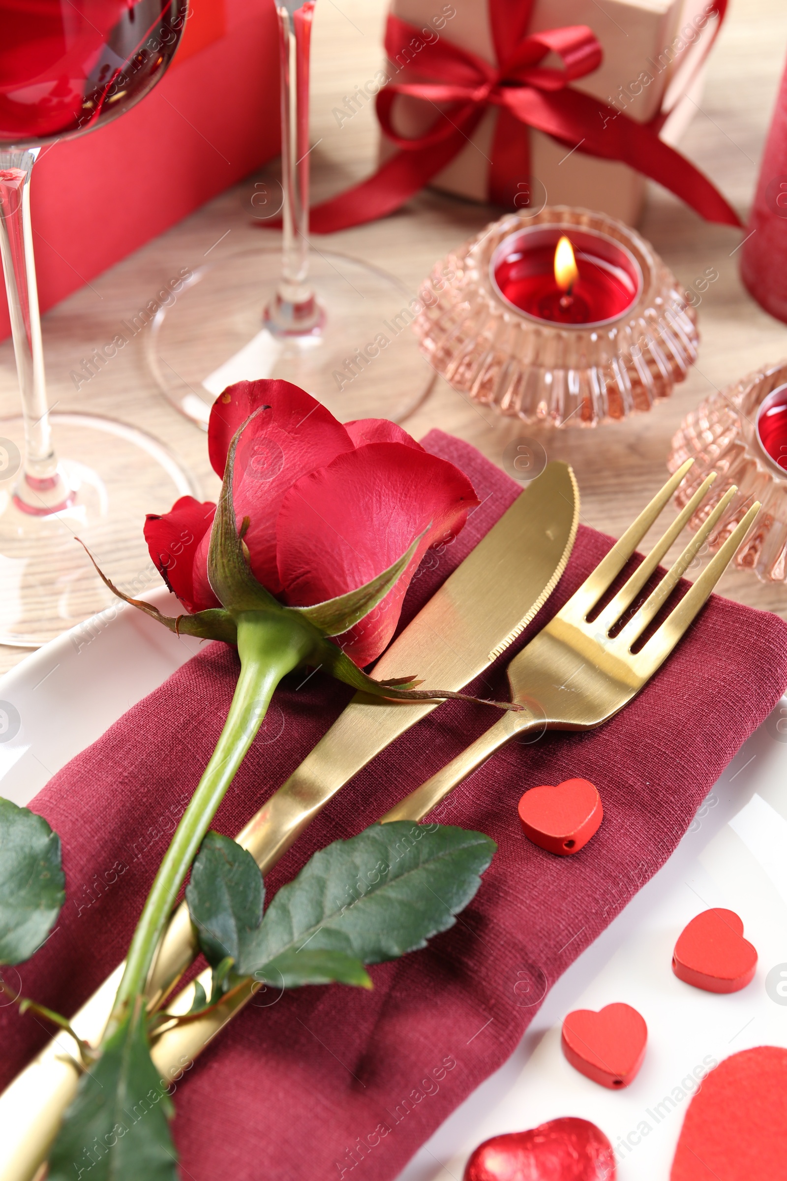 Photo of Romantic place setting with red rose on white table, closeup. Valentine's day celebration