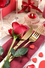 Photo of Romantic place setting with red rose on white table, closeup. Valentine's day celebration