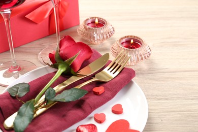 Photo of Romantic place setting with red rose on white table, closeup. Valentine's day celebration