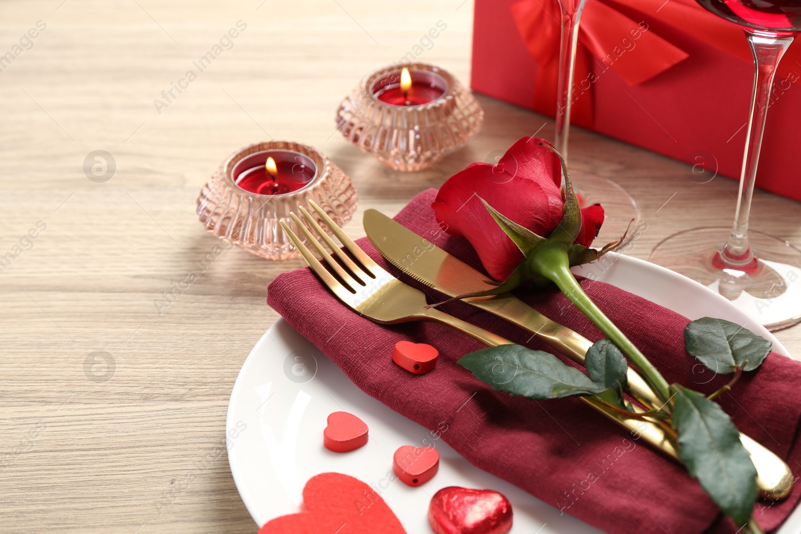 Photo of Romantic place setting with red rose on white table, closeup. Valentine's day celebration