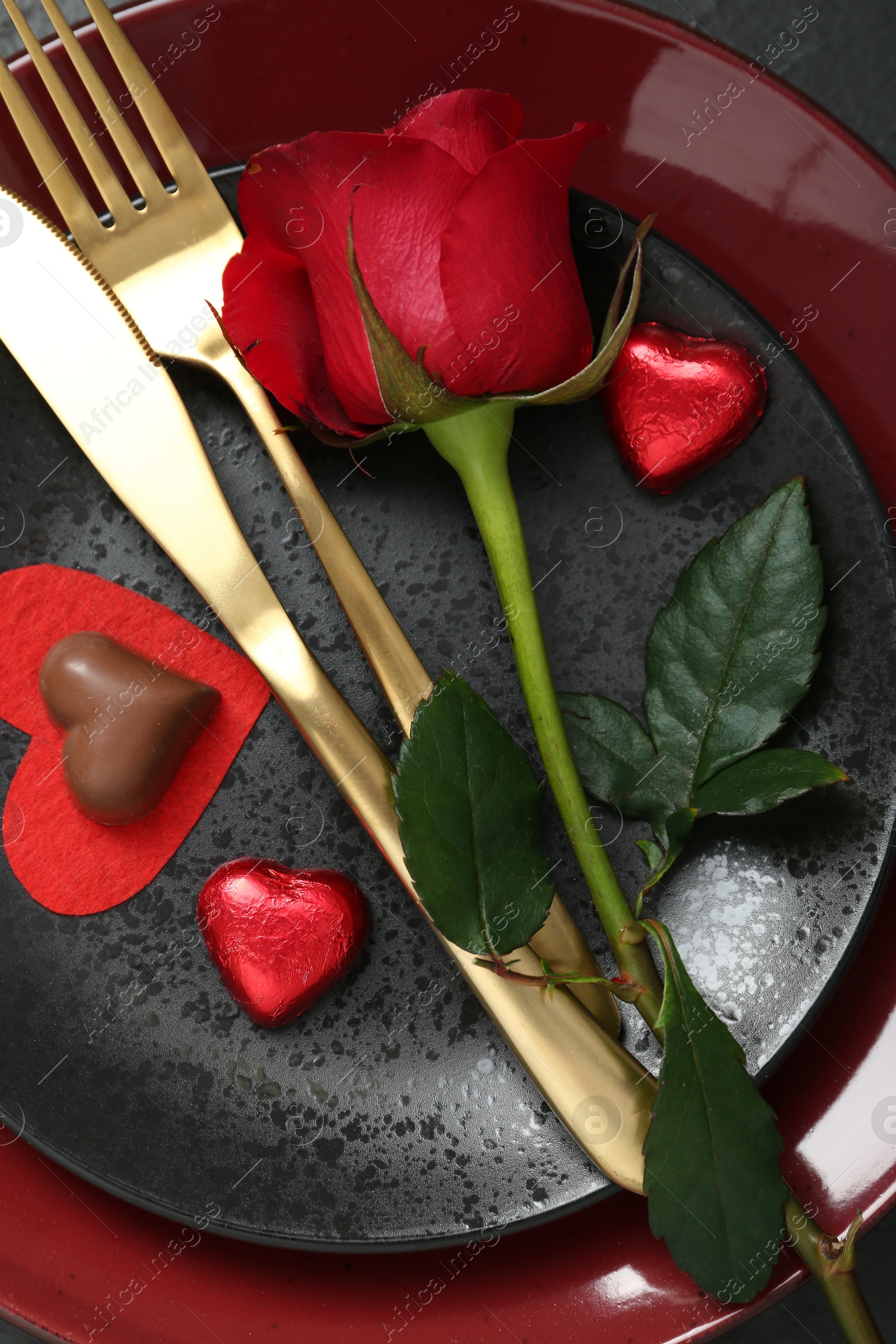 Photo of Romantic place setting with rose and plates on table, top view. Valentine's day celebration