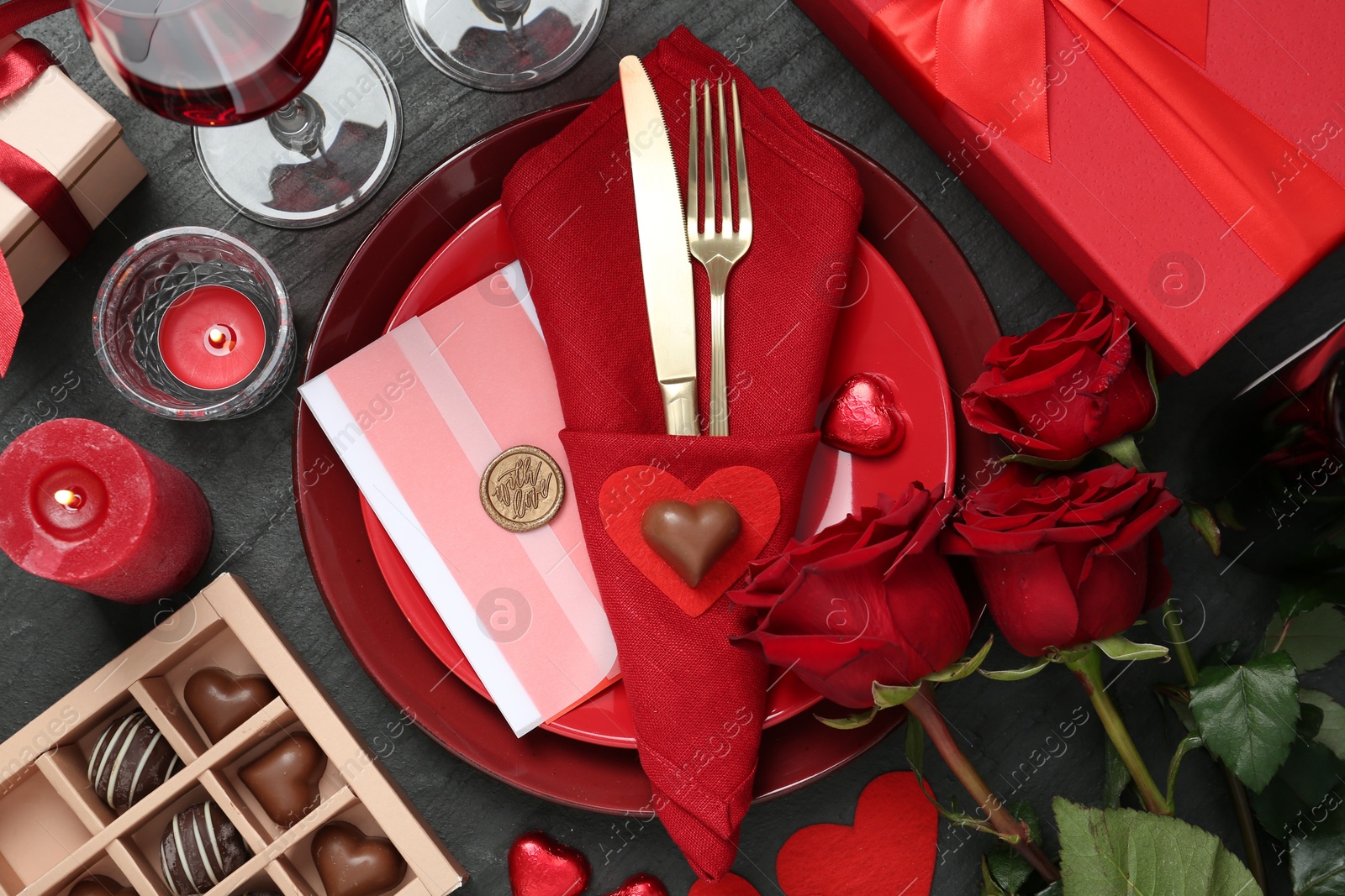 Photo of Romantic place setting with red roses on black table, flat lay. Valentine's day celebration