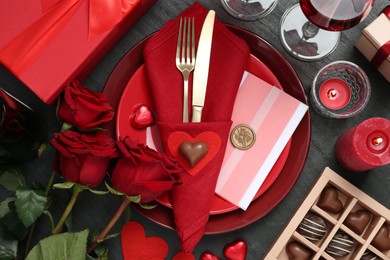 Photo of Romantic place setting with red roses on black table, flat lay. Valentine's day celebration