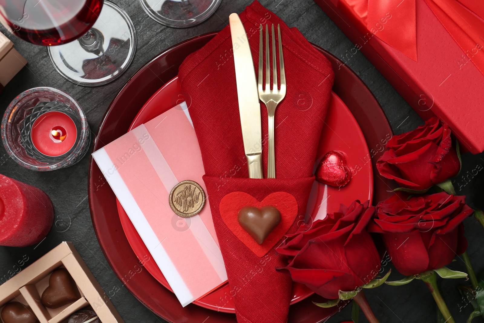 Photo of Romantic place setting with red roses on black table, flat lay. Valentine's day celebration