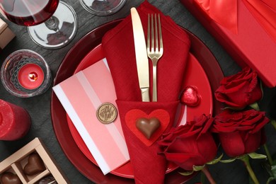 Photo of Romantic place setting with red roses on black table, flat lay. Valentine's day celebration