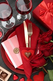 Photo of Romantic place setting with red roses on black table, flat lay. Valentine's day celebration