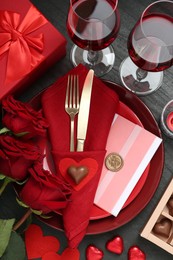 Photo of Romantic place setting with red roses on black table, flat lay. Valentine's day celebration