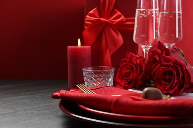 Photo of Romantic place setting with red roses on grey table, closeup. Valentine's day celebration