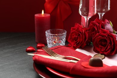 Photo of Romantic place setting with red roses on grey table, closeup. Valentine's day celebration