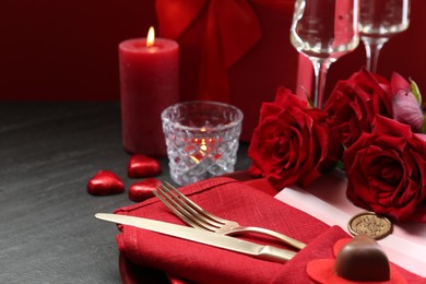 Photo of Romantic place setting with red roses on grey table, closeup. Valentine's day celebration