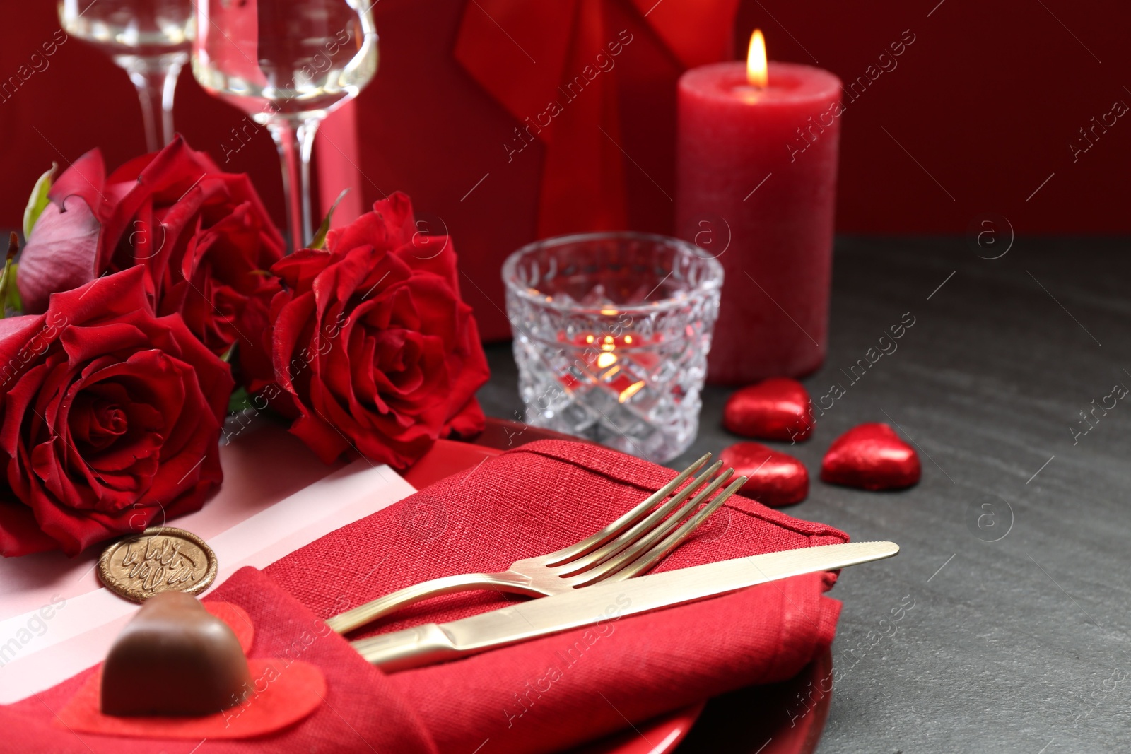 Photo of Romantic place setting with red roses on grey table, closeup. Valentine's day celebration