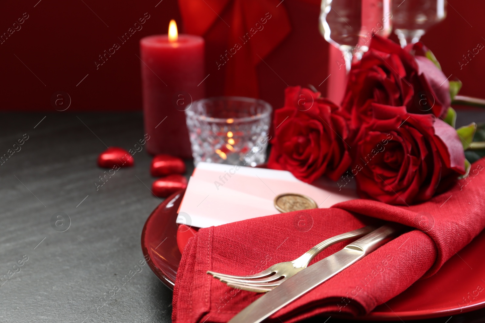 Photo of Romantic place setting with red roses on grey table, closeup. Valentine's day celebration