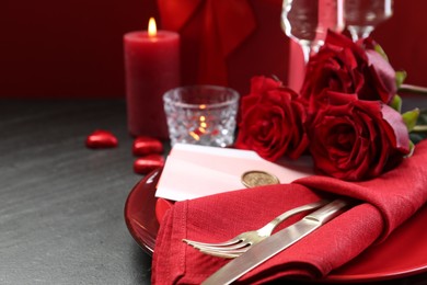 Photo of Romantic place setting with red roses on grey table, closeup. Valentine's day celebration