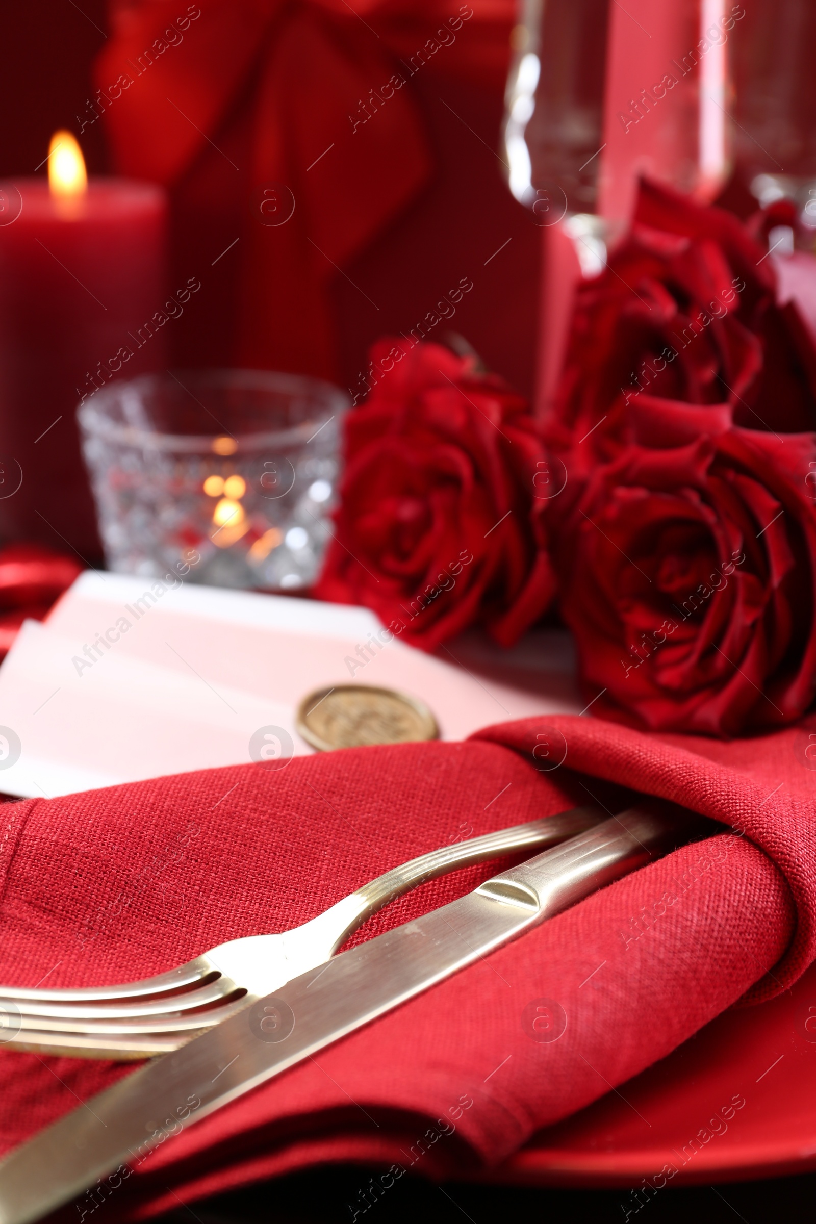 Photo of Romantic place setting with red roses on table, closeup. Valentine's day celebration