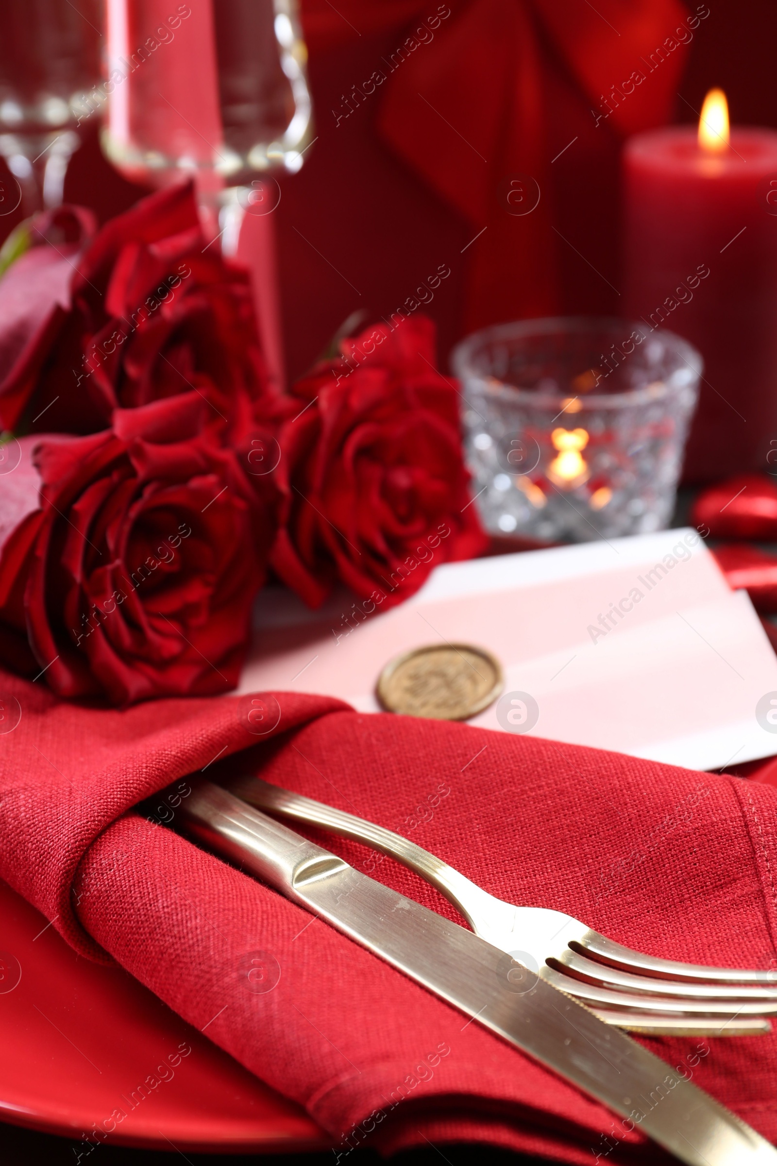 Photo of Romantic place setting with red roses on table, closeup. Valentine's day celebration