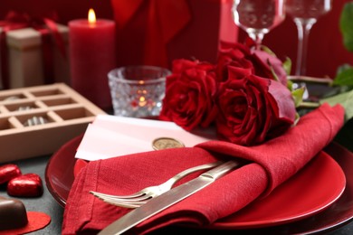 Photo of Romantic place setting with red roses on grey table, closeup. Valentine's day celebration