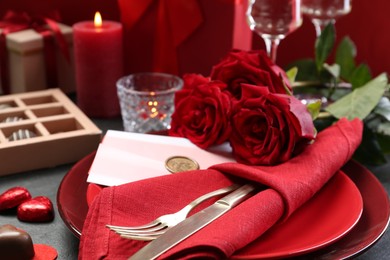 Photo of Romantic place setting with red roses on grey table, closeup. Valentine's day celebration