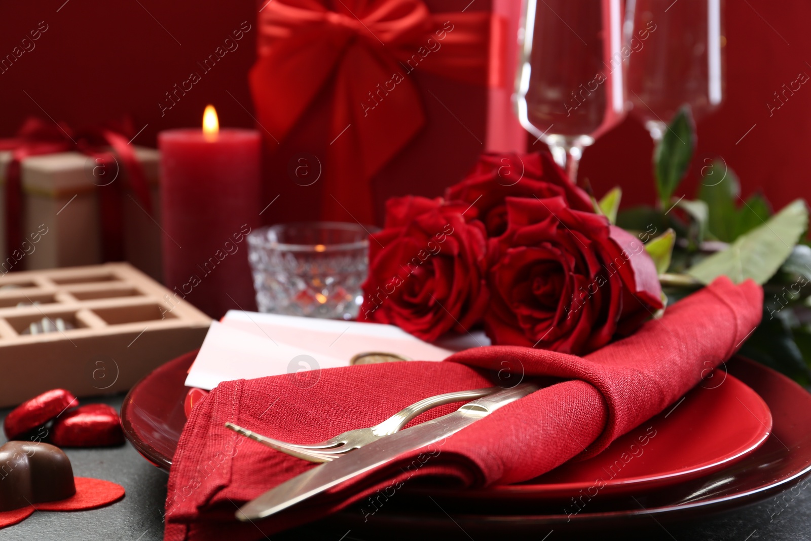 Photo of Romantic place setting with red roses on grey table, closeup. Valentine's day celebration