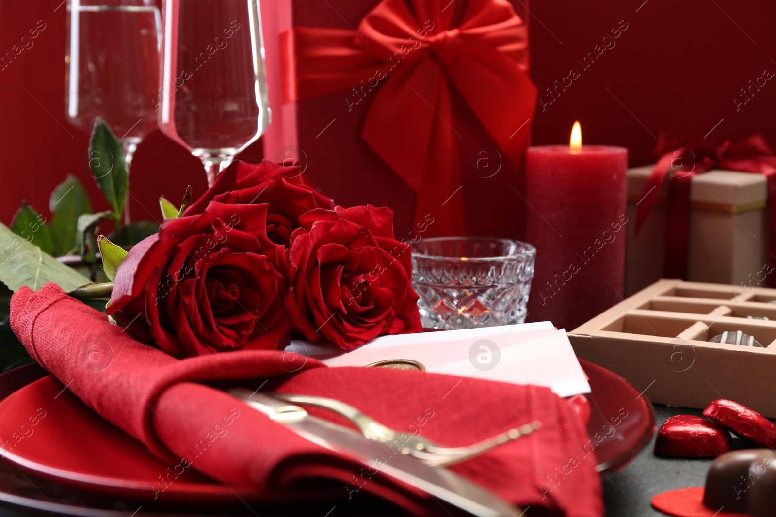 Photo of Romantic place setting with red roses on grey table, closeup. Valentine's day celebration