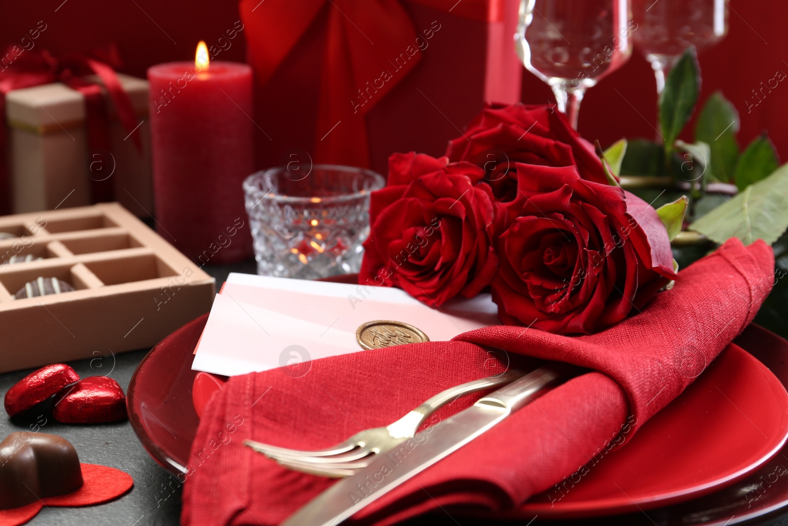 Photo of Romantic place setting with red roses on grey table, closeup. Valentine's day celebration