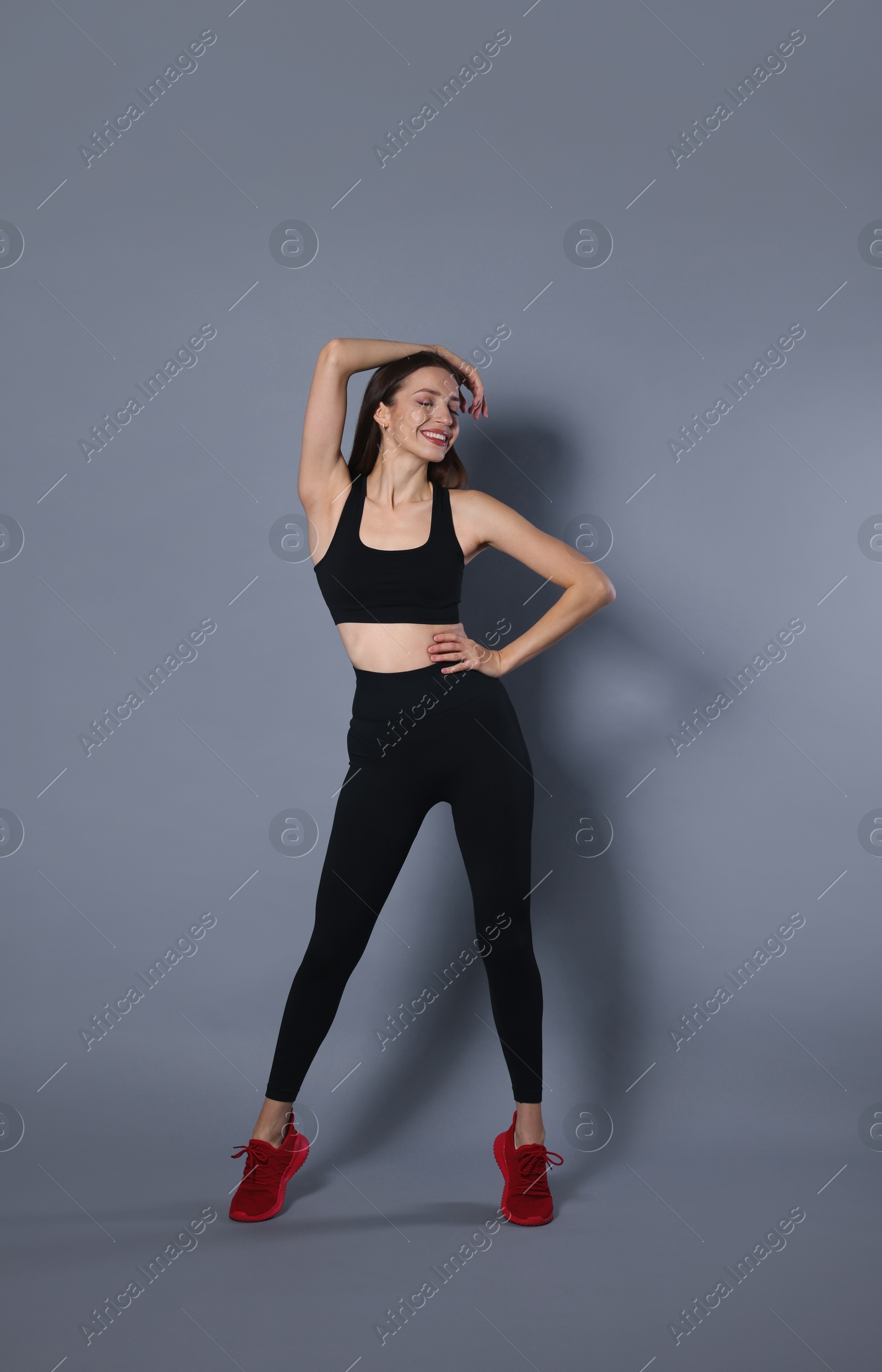 Photo of Beautiful woman in stylish sportswear on grey background