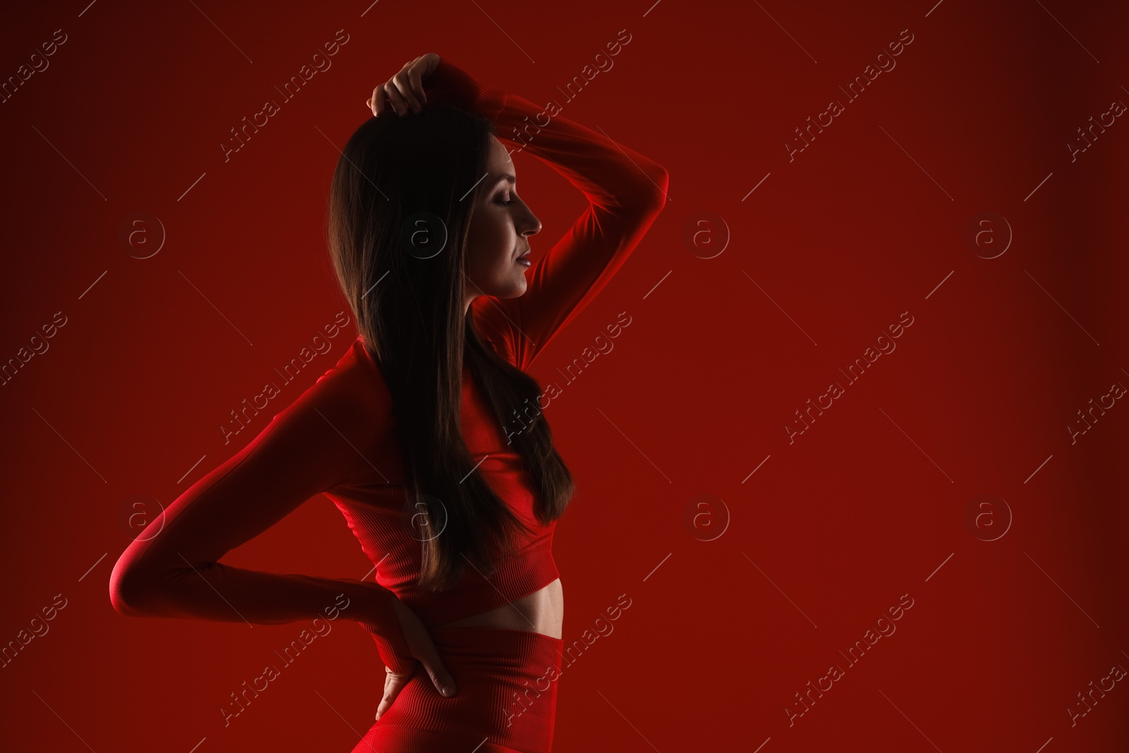 Photo of Beautiful woman in stylish sportswear on red background. Space for text