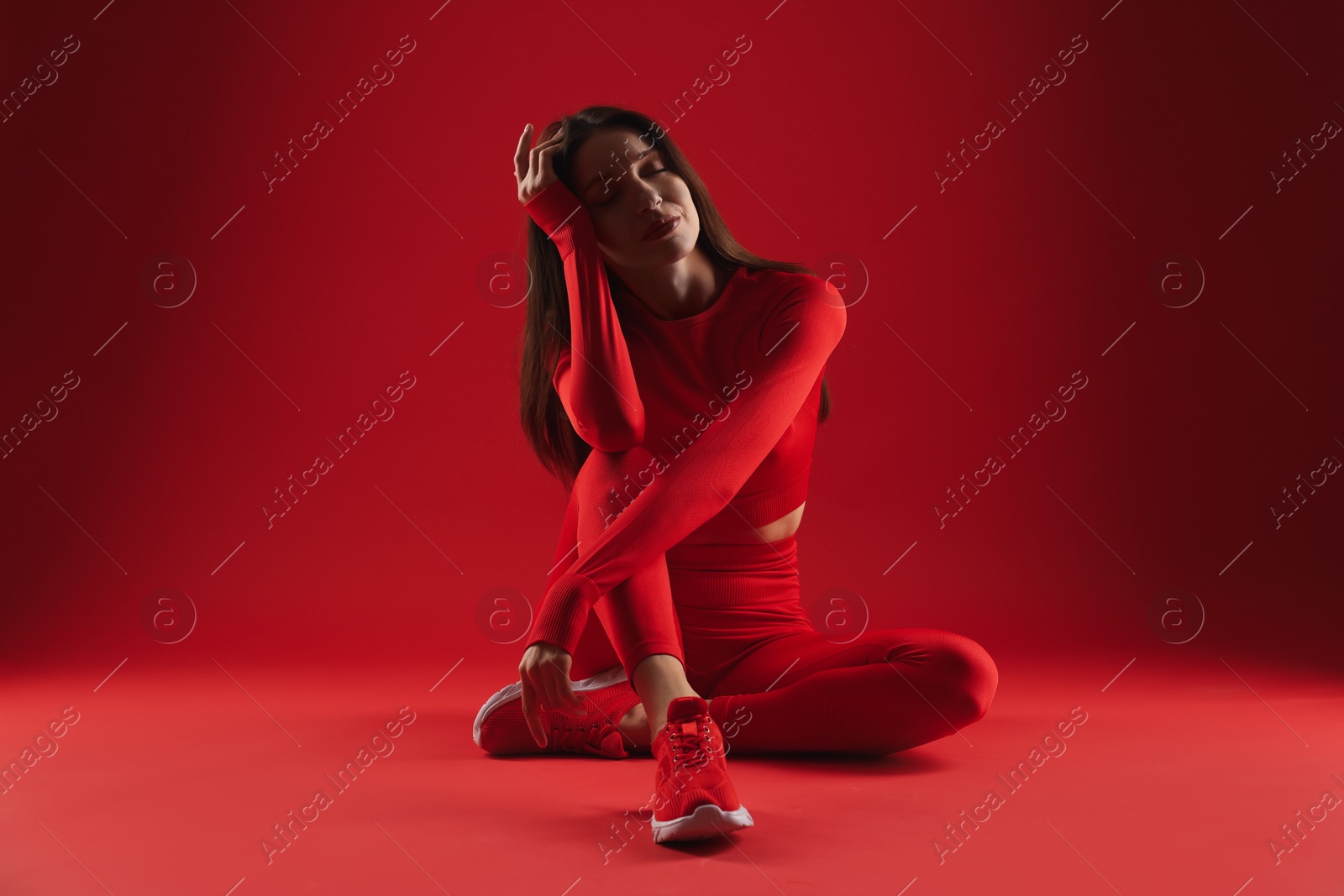 Photo of Beautiful woman in stylish sportswear on red background