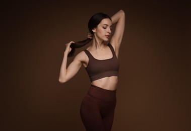 Photo of Beautiful woman in stylish sportswear on brown background