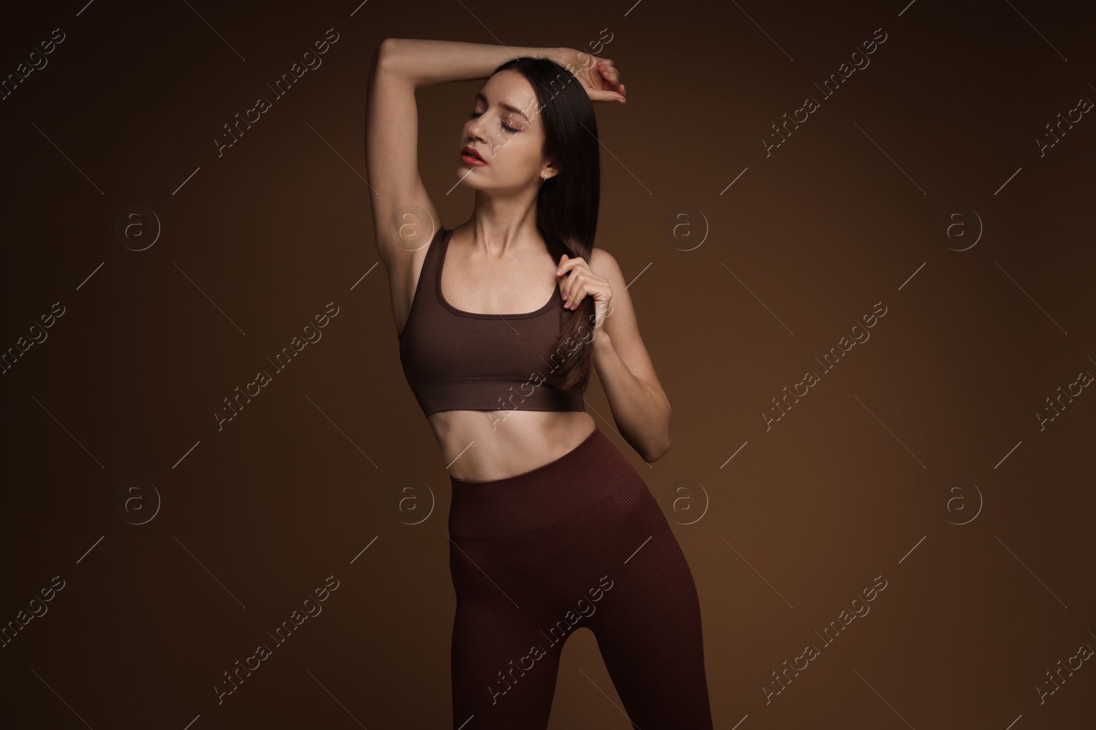 Photo of Beautiful woman in stylish sportswear on brown background