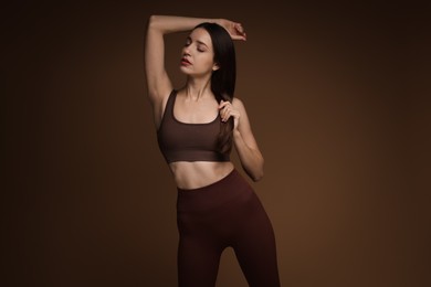 Photo of Beautiful woman in stylish sportswear on brown background