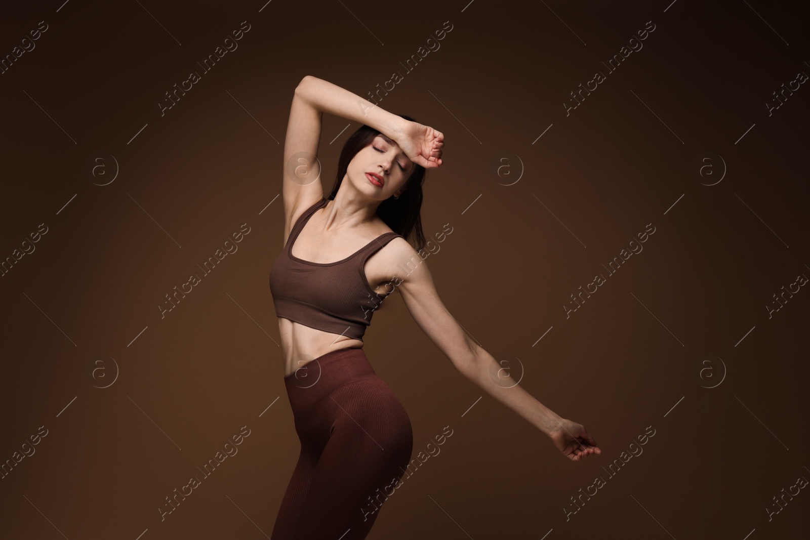 Photo of Beautiful woman in stylish sportswear on brown background