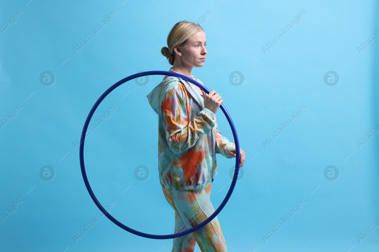 Photo of Beautiful young woman with hula hoop on light blue background