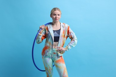 Photo of Beautiful young woman with hula hoop on light blue background