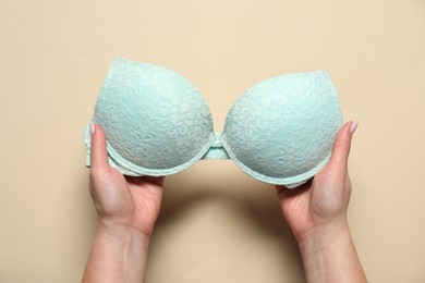 Photo of Woman with turquoise bra on beige background, top view