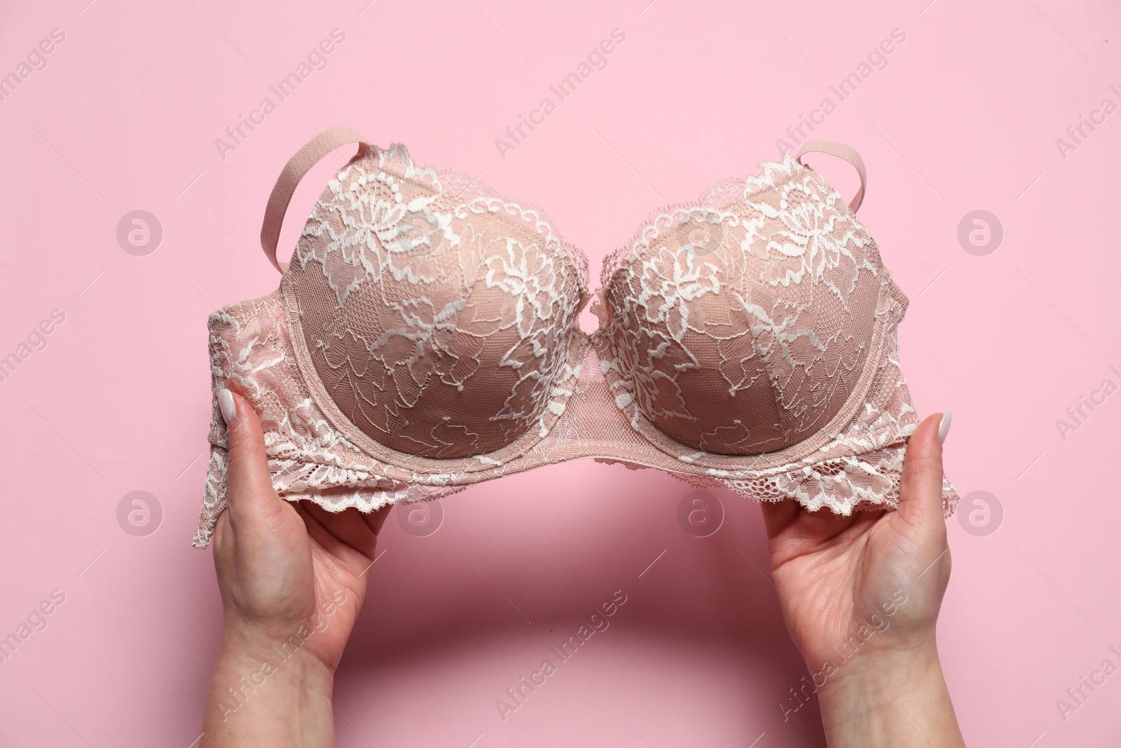 Photo of Woman with lace bra on pale pink background, top view