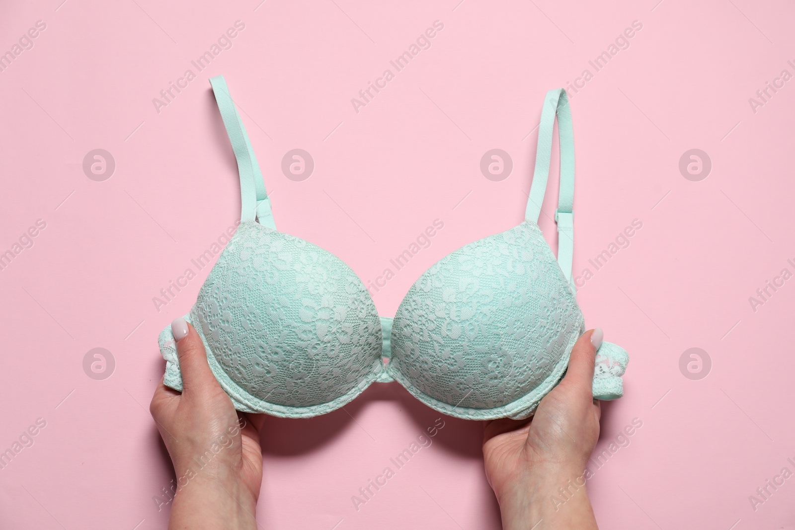 Photo of Woman with turquoise bra on pale pink background, top view