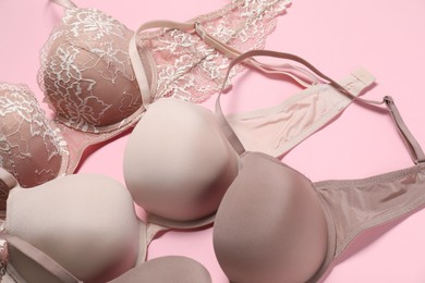 Photo of Beautiful bras on pale pink background, above view