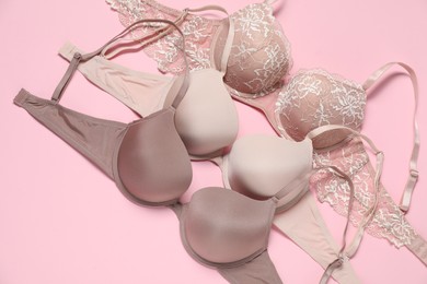 Photo of Beautiful bras on pale pink background, flat lay