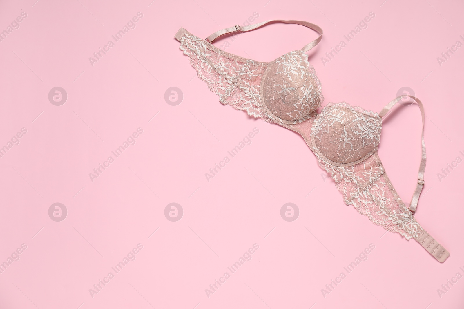 Photo of Beautiful lace bra on pale pink background, top view. Space for text