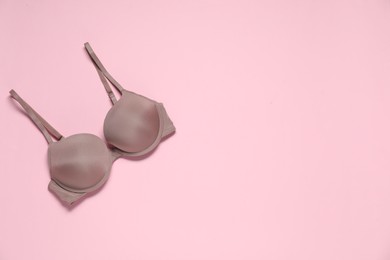 Photo of Beautiful dark beige bra on pale pink background, top view. Space for text