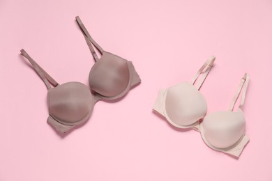 Photo of Beautiful bras on pale pink background, flat lay