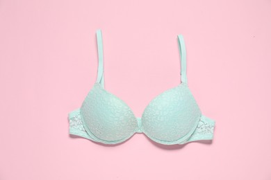 Photo of Beautiful turquoise bra on pink background, top view