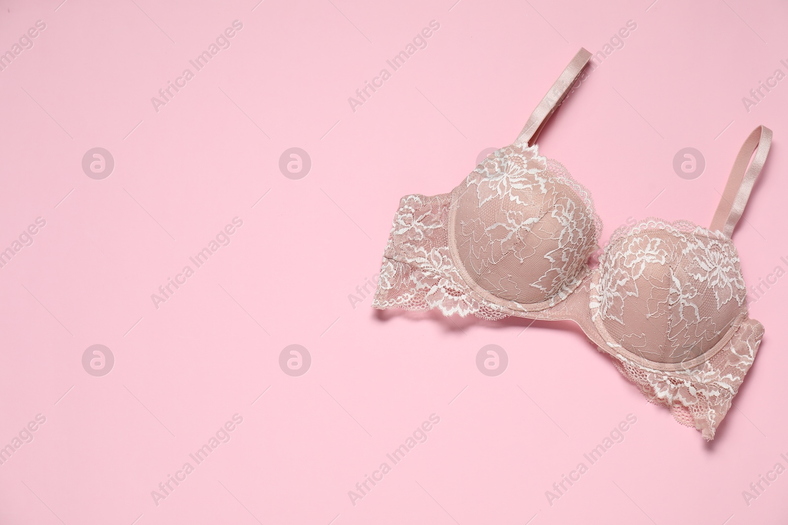 Photo of Beautiful lace bra on pale pink background, top view. Space for text