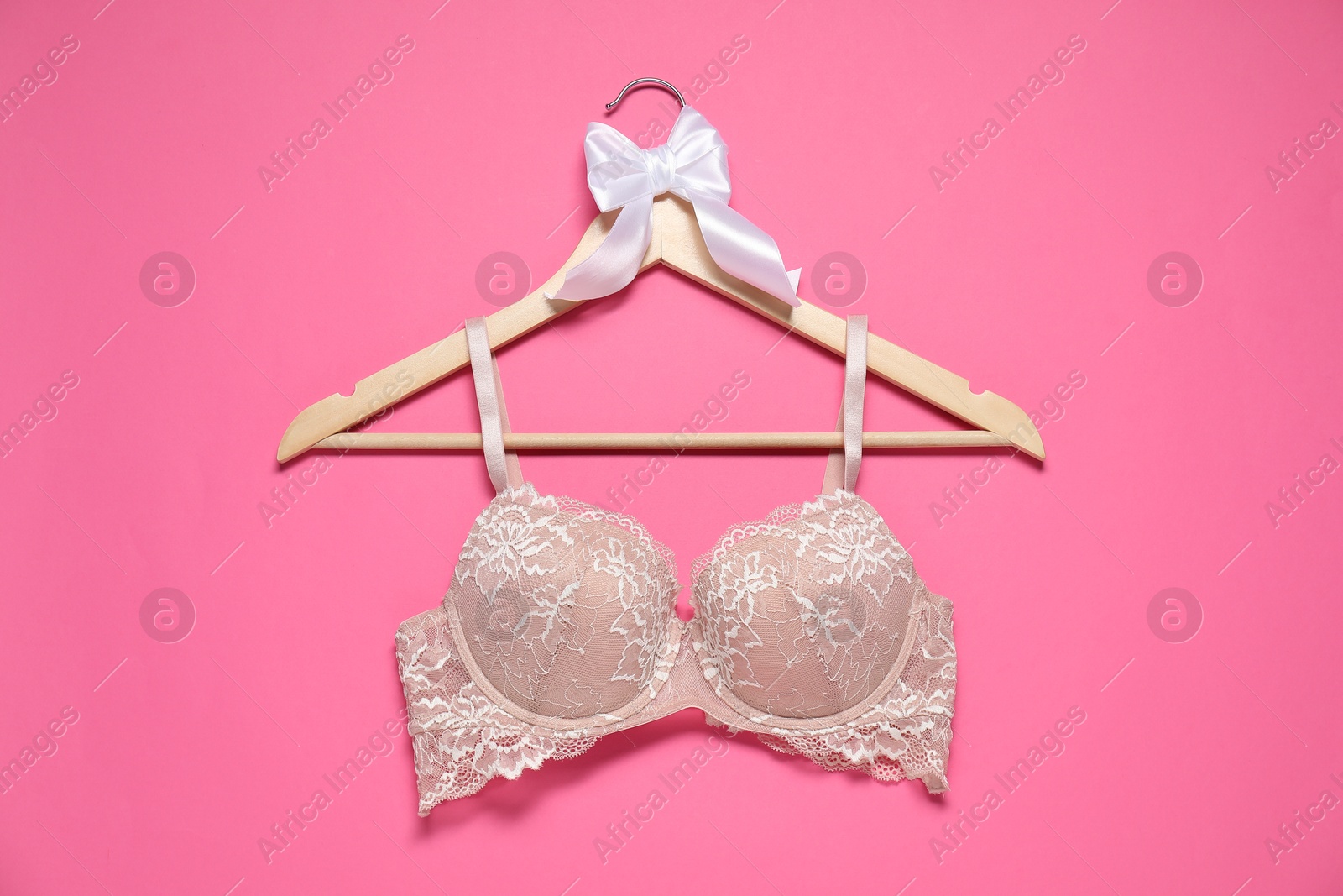 Photo of Hanger with beautiful lace bra on pink background, top view