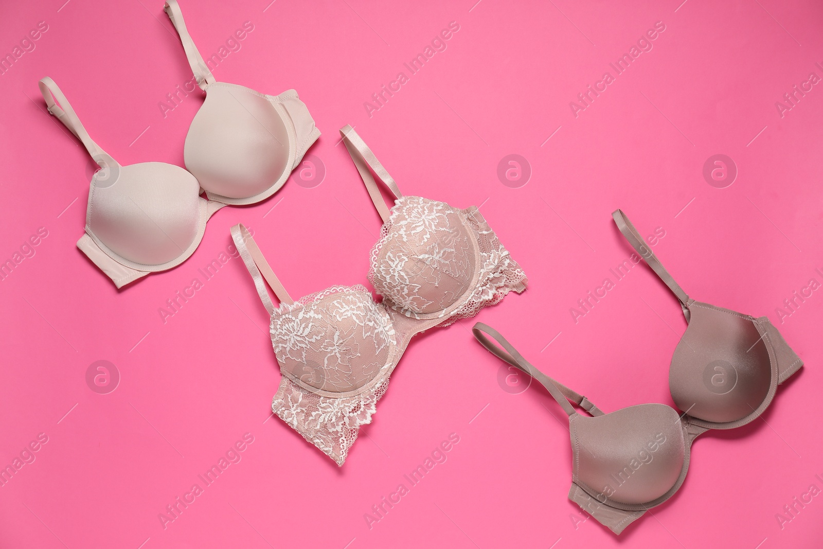 Photo of Beautiful bras on pink background, flat lay