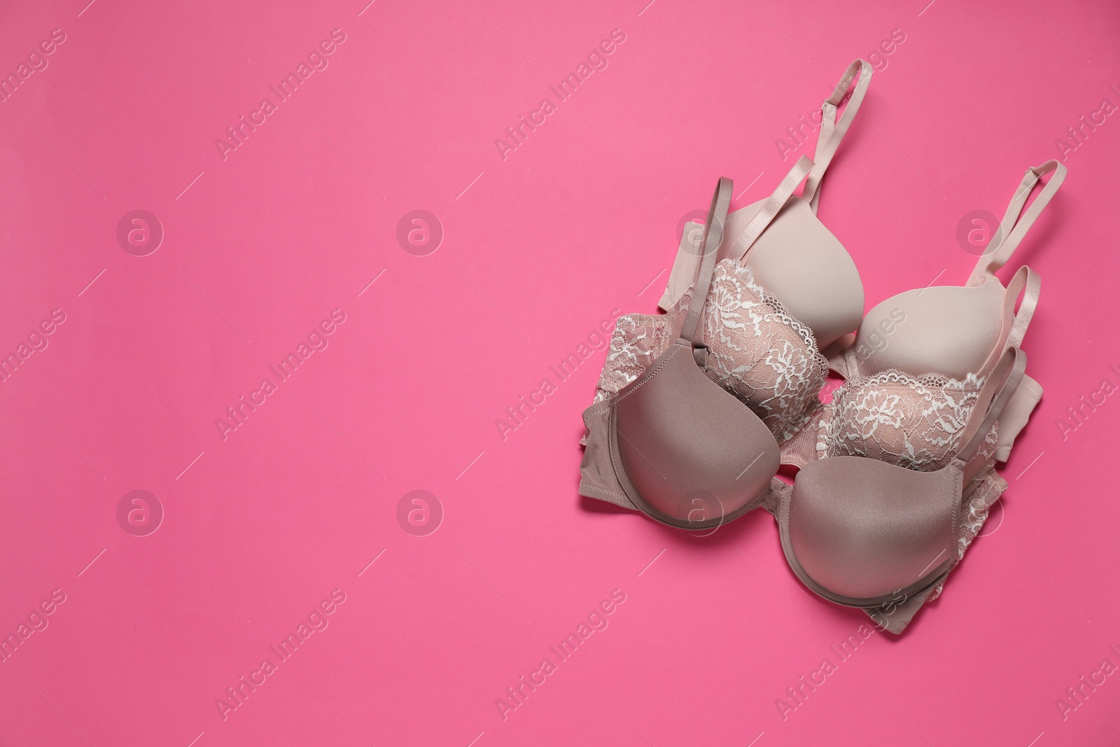 Photo of Beautiful bras on pink background, flat lay. Space for text